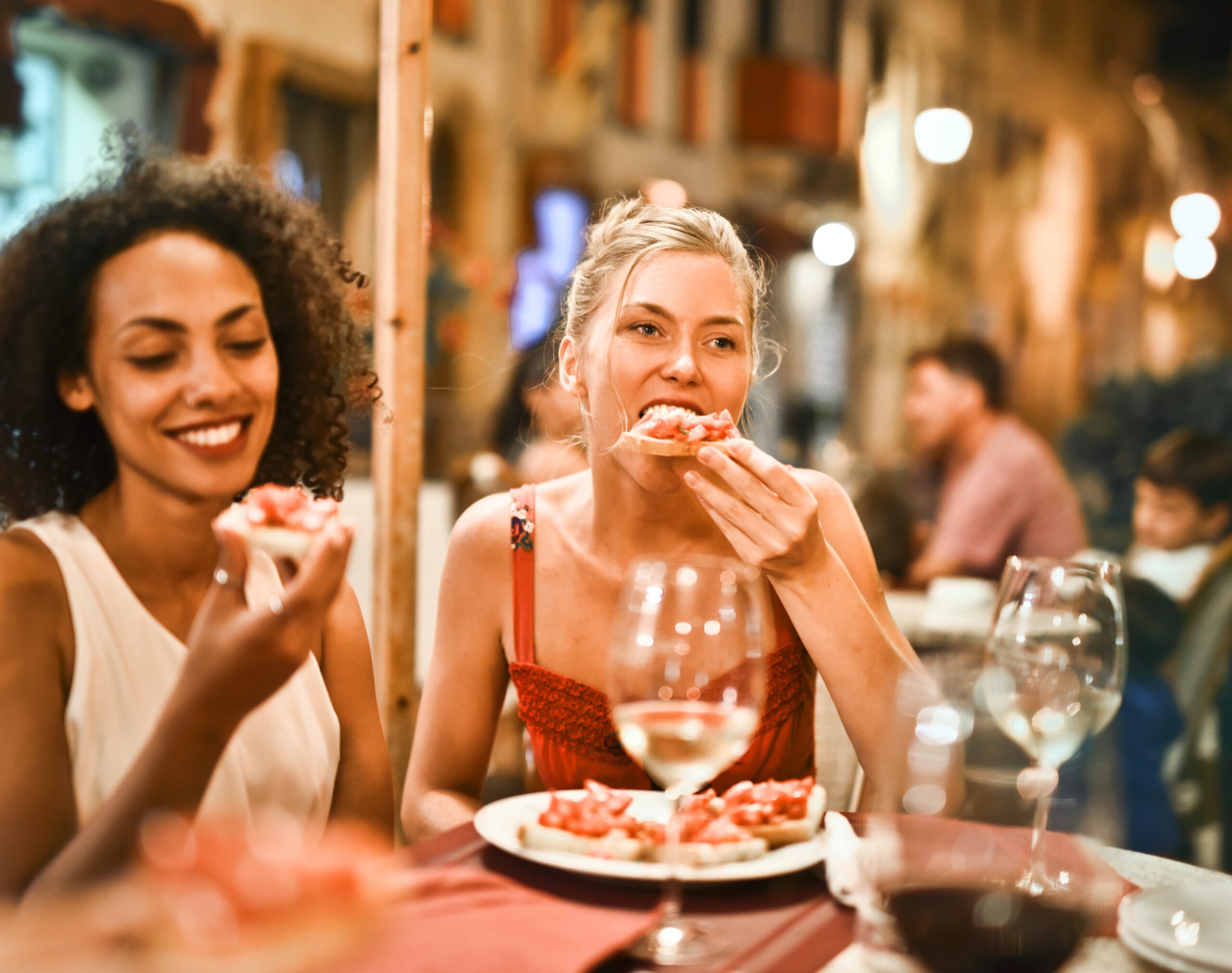 Dwie młode kobiety z uśmiechami na twarzy spożywają posiłek w jednej z częstochowskich restauracji
