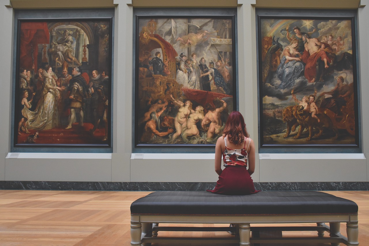 Dziewczyna siedząca i patrząca na obrazy w jednym w częstochowskich muzeów